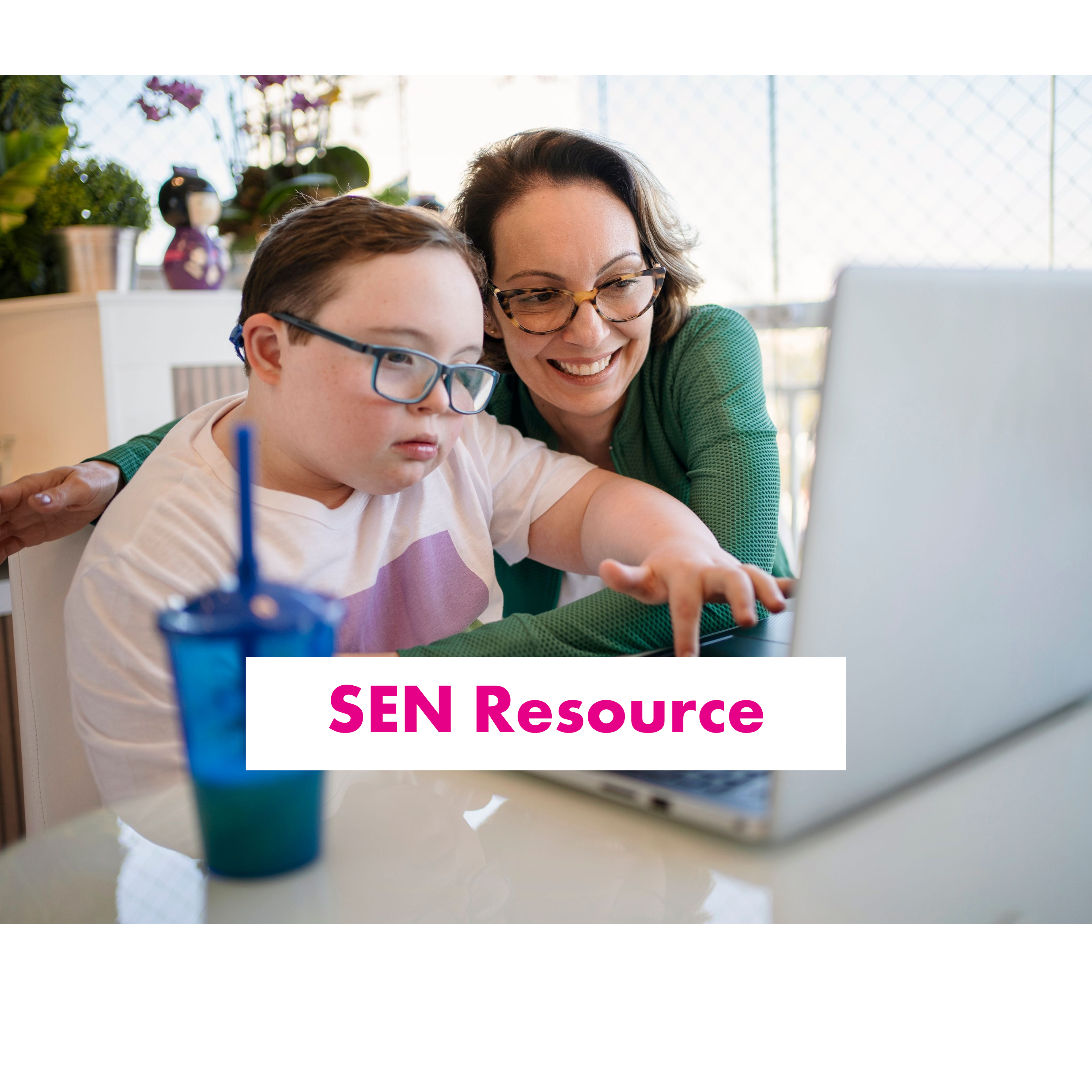 Boy sat typing on a laptop, aided by a smiling adult 