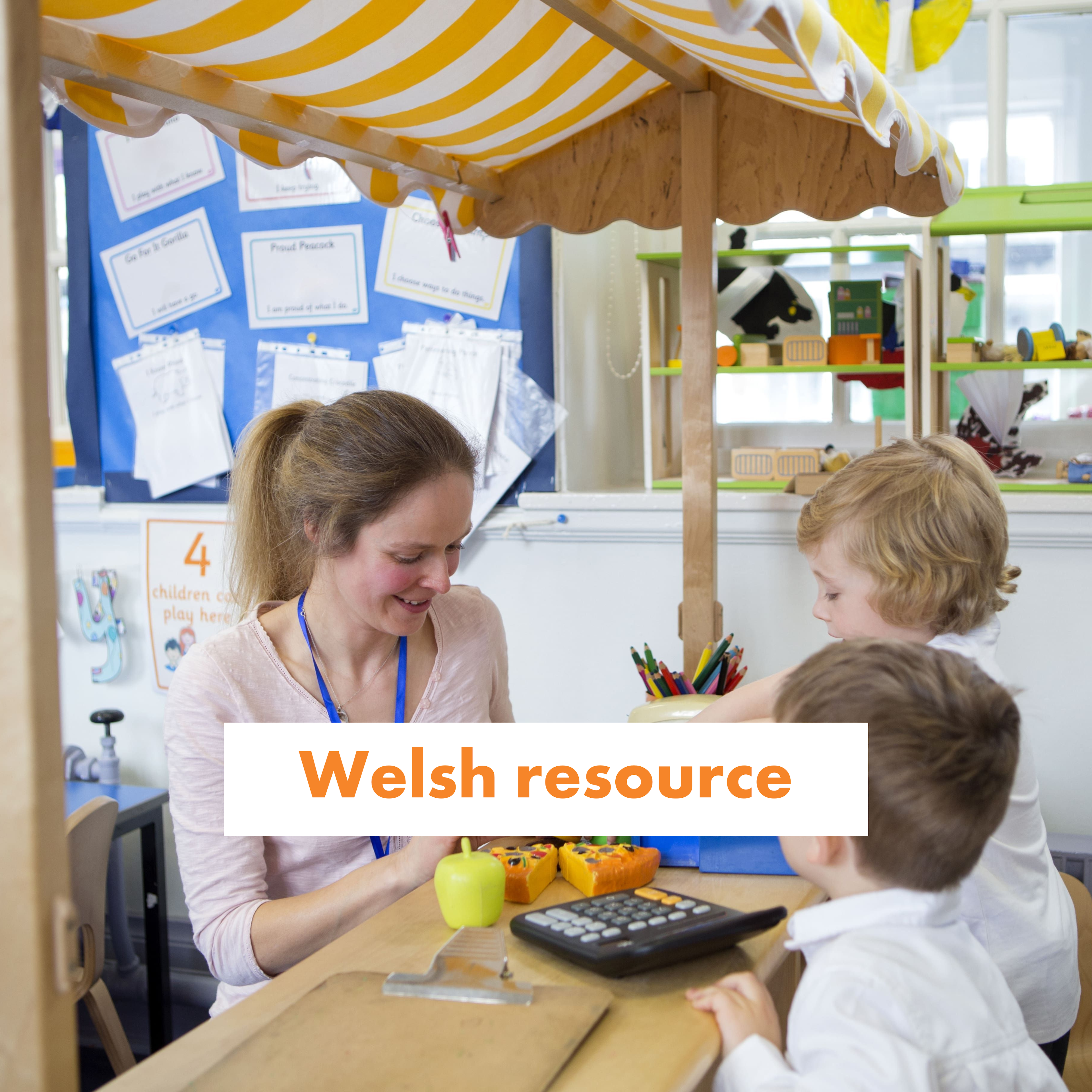 A teacher and two young children play in a role play shop with toy till.