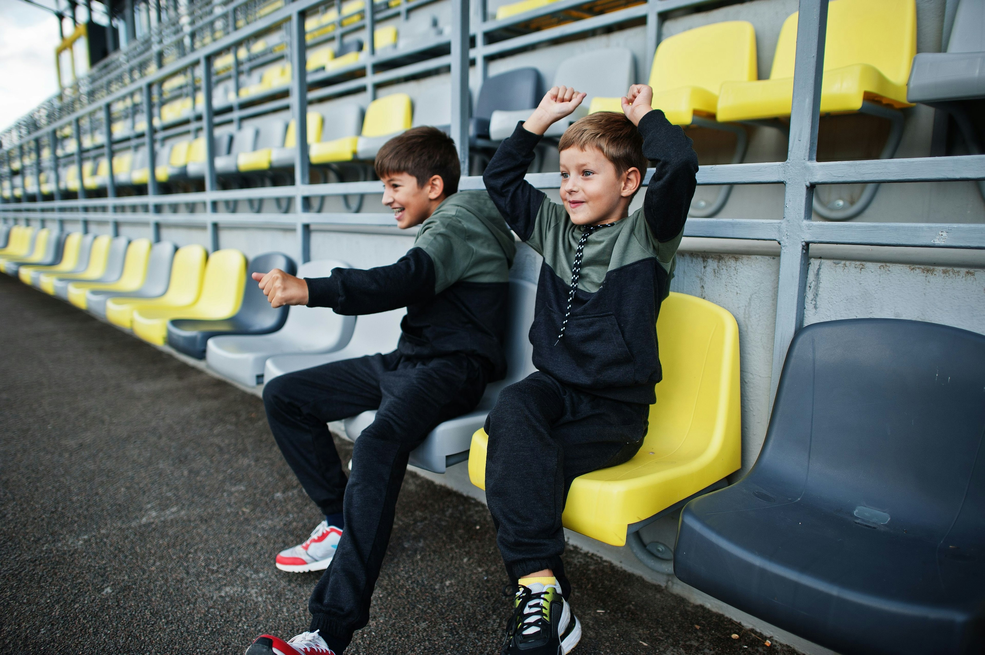 Two boys in the stands of a football stadium.