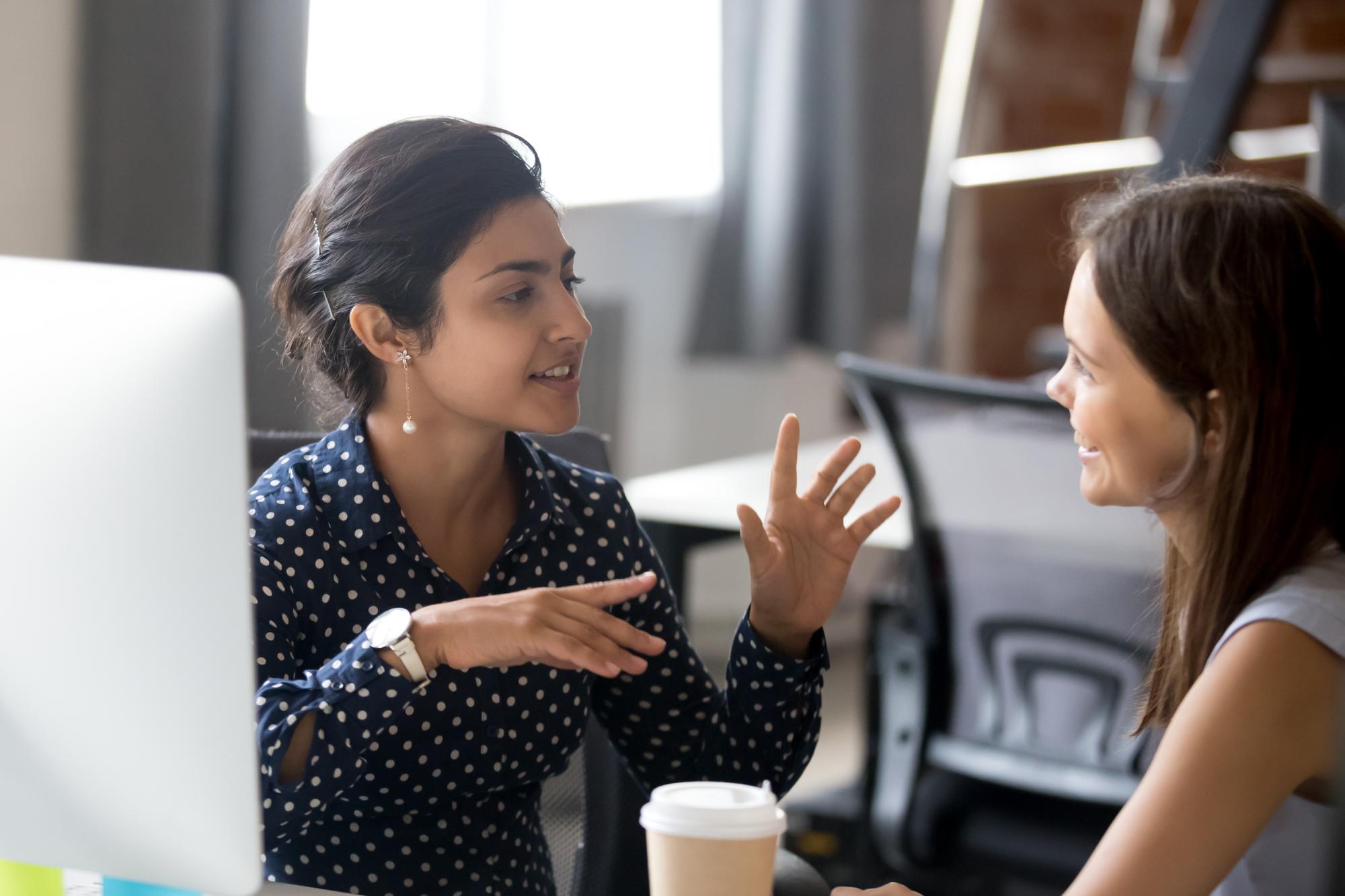 Two ladies talking in front of computer screen