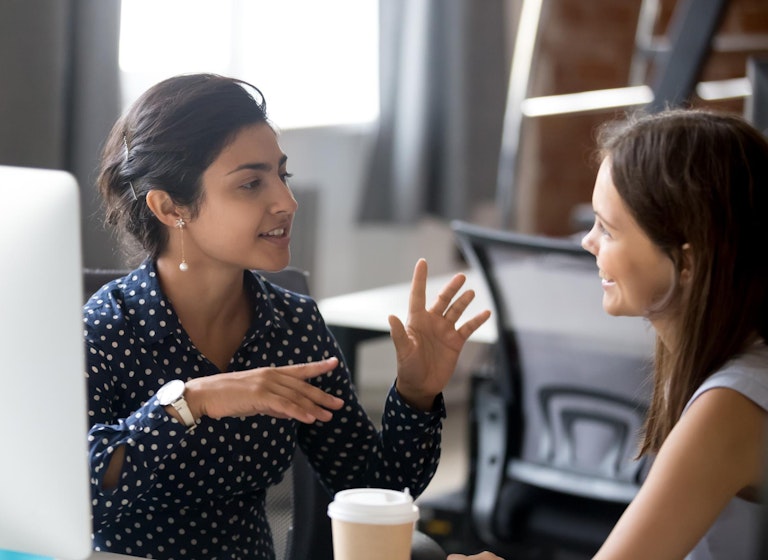 Two ladies talking in front of computer screen