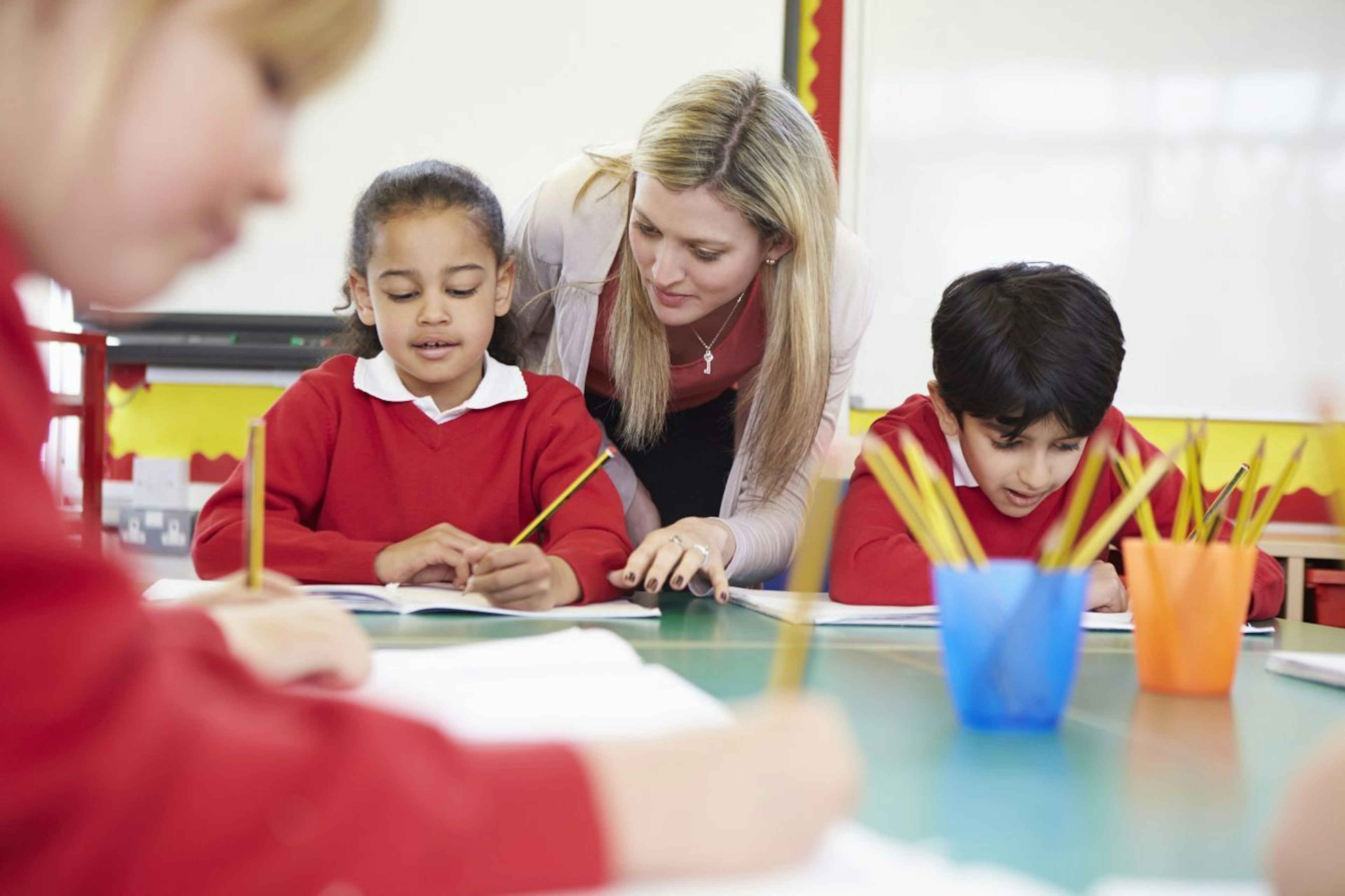 Teacher helping a children who is writing